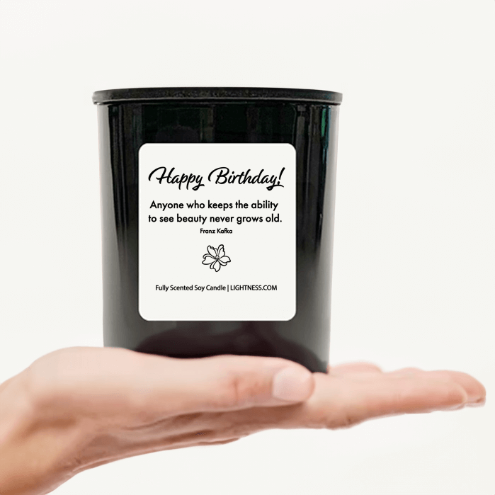 Candle in black glass jar on hand with Birthday quote - Anyone who keeps the ability to see beauty never grows old.