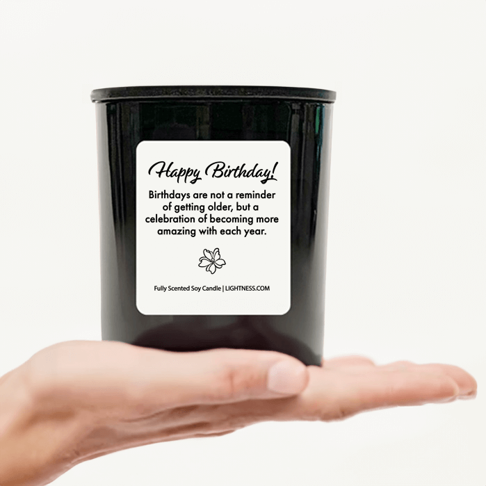 Candle in black glass jar on hand with Birthday quote - Birthdays are not a reminder of getting older, but a celebration of becoming more amazing with each year.