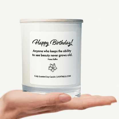 Candle in white glass jar on hand with Birthday quote - Anyone who keeps the ability to see beauty never grows old.