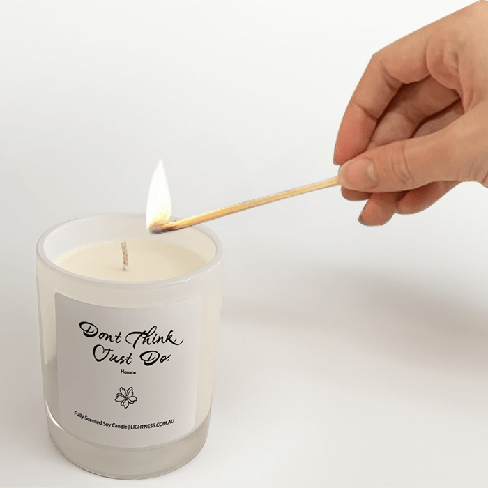 Candle in  white glass jar and quote about to be lit with a match