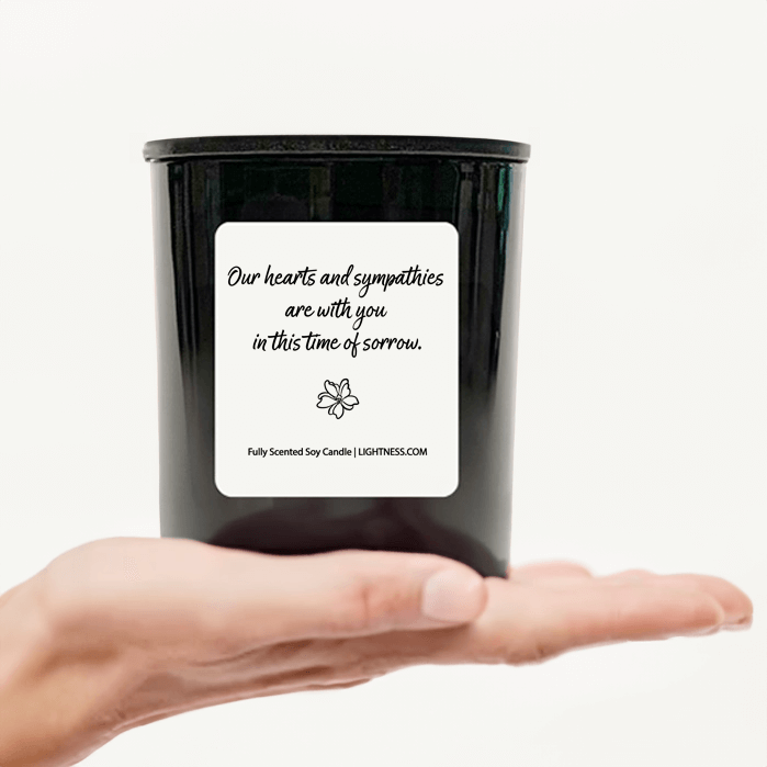 Candle in black glass jar on hand with Condolence quote - Our hearts are with you in this time of sorrow.