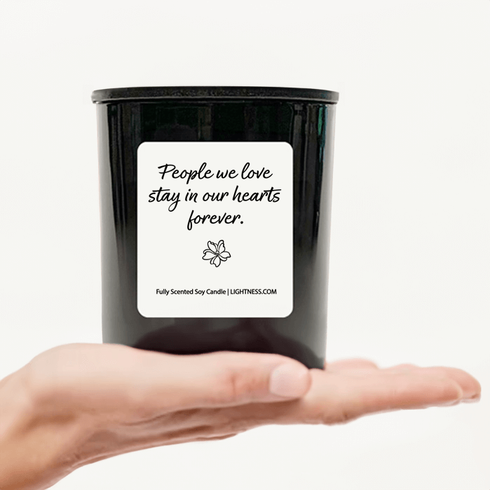 Candle in black glass jar on hand with Condolence quote - People we love stay in our hearts forever.