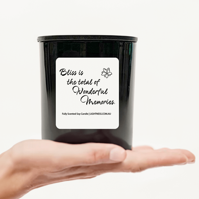 Candle in black glass jar on hand with Happiness quote - Bliss is the total of wonderful memories.