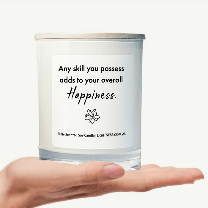 Candle in white glass jar on hand with Happiness quote - Any skill you possess adds to your overall happiness.