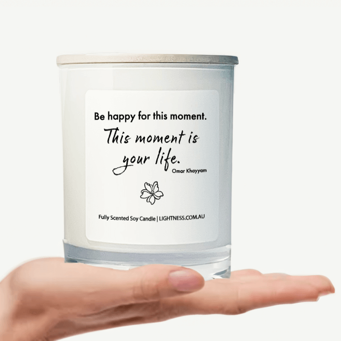 Candle in white glass jar on hand with Happiness quote - Be happy for this moment. This moment is your life.