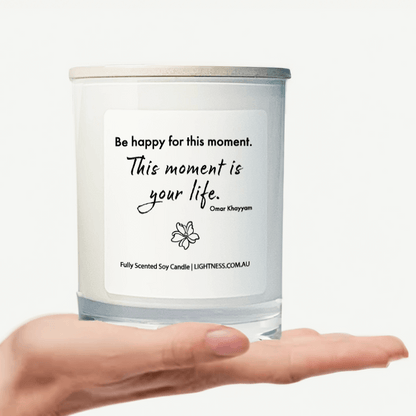 Candle in white glass jar on hand with Happiness quote - Be happy for this moment. This moment is your life.