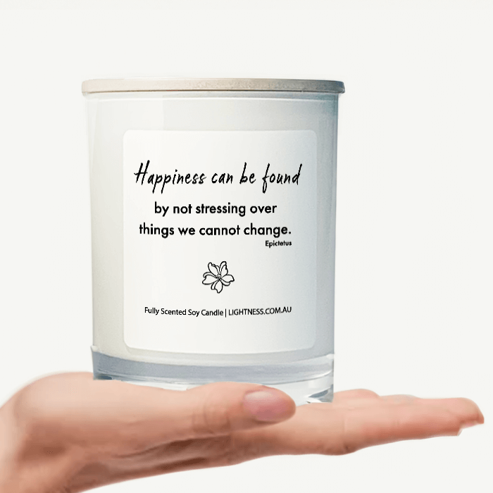 Candle in white glass jar on hand with Happiness quote - Happiness can be found by not stressing over things we cannot change.