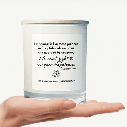 Candle in white glass jar on hand with Happiness quote - Happiness is like those palaces in fairy tales whose gates are guarded by dragons; we must fight in order to conquer it.