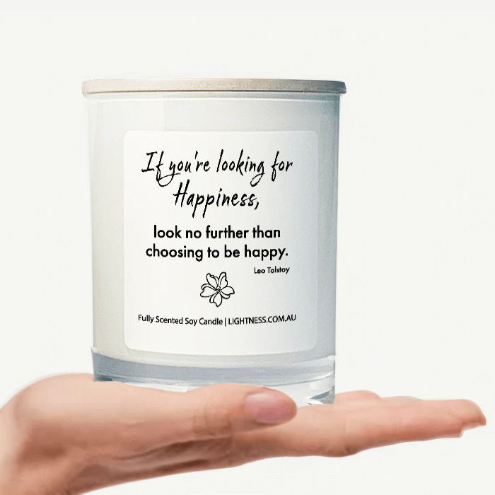 Candle in white glass jar on hand with Happiness quote - If you're looking for happiness, look no further than choosing to be happy.