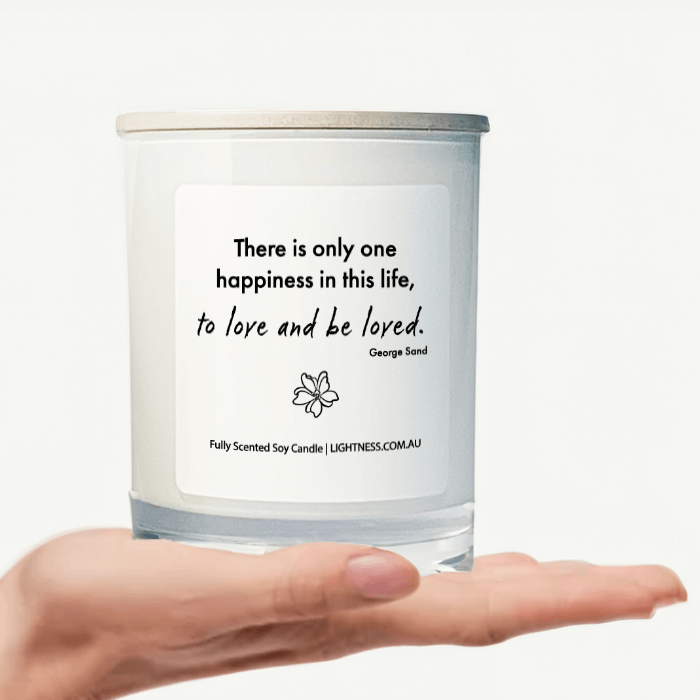 Candle in white glass jar on hand with Happiness quote - There is only one happiness in this life, to love and be loved.