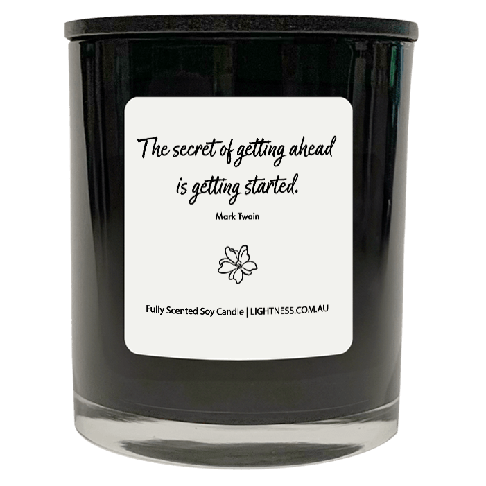 Candle in black glass jar with motivational quote - The secret of getting ahead is getting started.