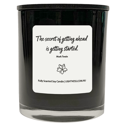 Candle in black glass jar with motivational quote - The secret of getting ahead is getting started.