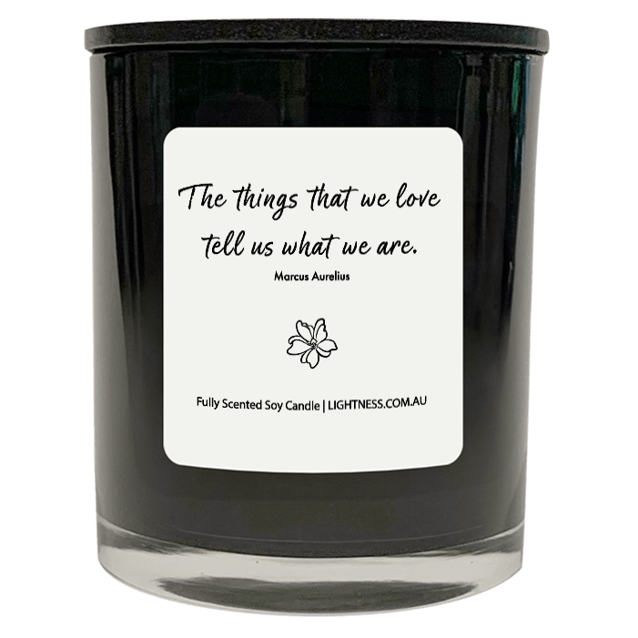 Candle in black glass jar with motivational quote - The things that we love tell us what we are.