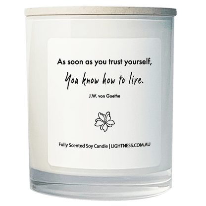 Candle in white glass jar with motivational quote - As soon as you trust yourself, you know how to live.