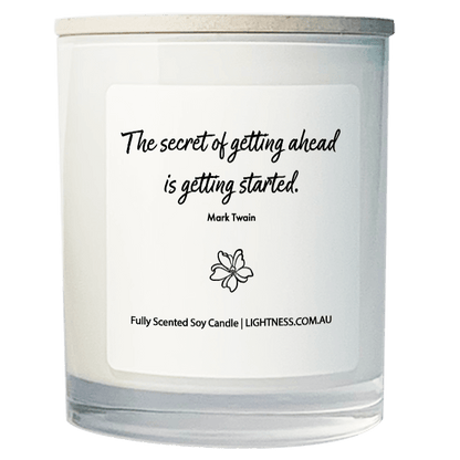 Candle in white glass jar with motivational quote - The secret of getting ahead is getting started.