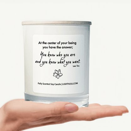 Candle in white glass jar on hand with motivational quote - At the center of your being you have the answer; you know who you are and you know what you want.