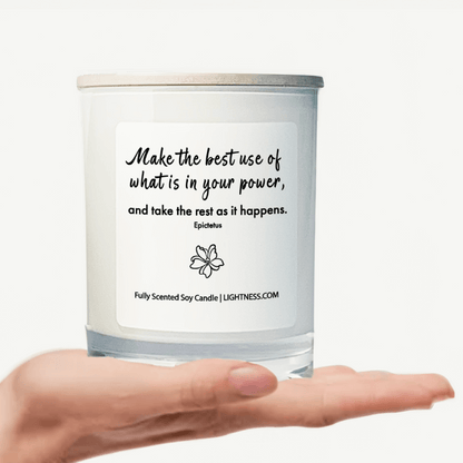 Candle in white glass jar on hand with motivational quote - Make the best use of what is in your power, and take the rest as it happens.