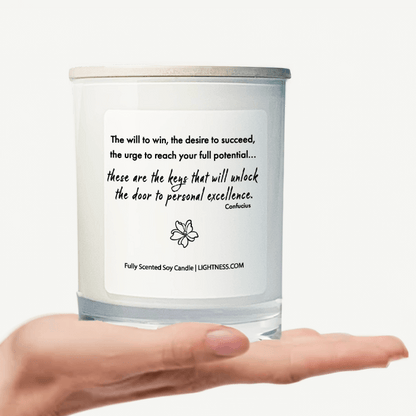 Candle in white glass jar on hand with motivational quote - The will to win, the desire to succeed, the urge to reach your full potential... these are the keys that will unlock the door to personal excellence.