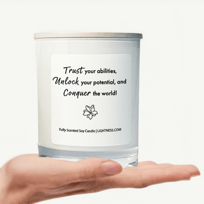 Candle in white glass jar on hand with motivational quote - Trust your abilities, unlock your potential, and conquer the world!