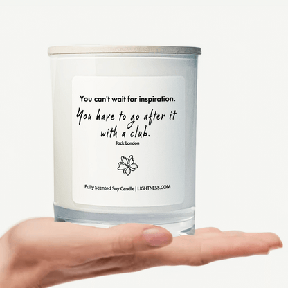 Candle in white glass jar on hand with motivational quote - You can't wait for inspiration. You have to go after it with a club.