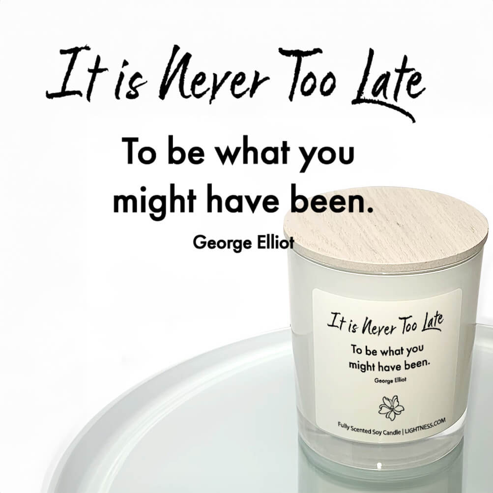 Candle in white glass jar reflected in mirror with motivational quote - It is never too late to be what you might have been.