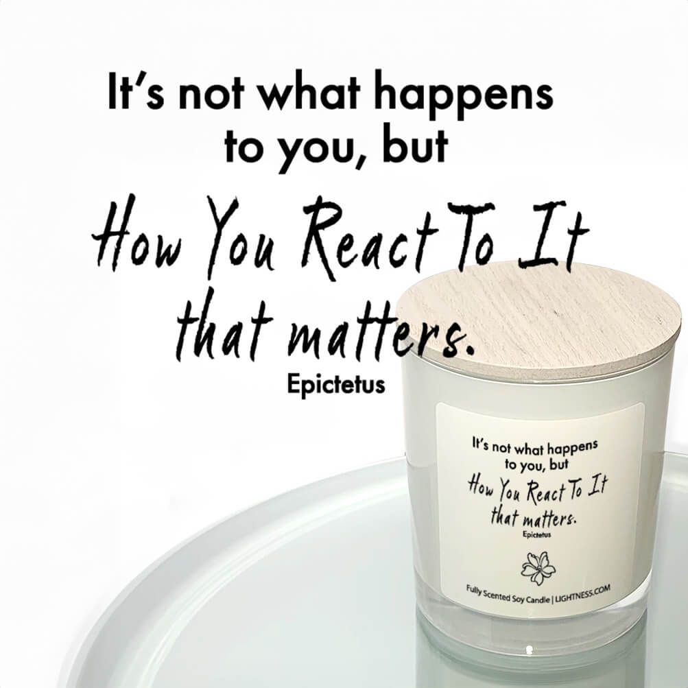 Candle in white glass jar reflected in mirror with motivational quote - It's not what happens to you, but how you react to it that matters.