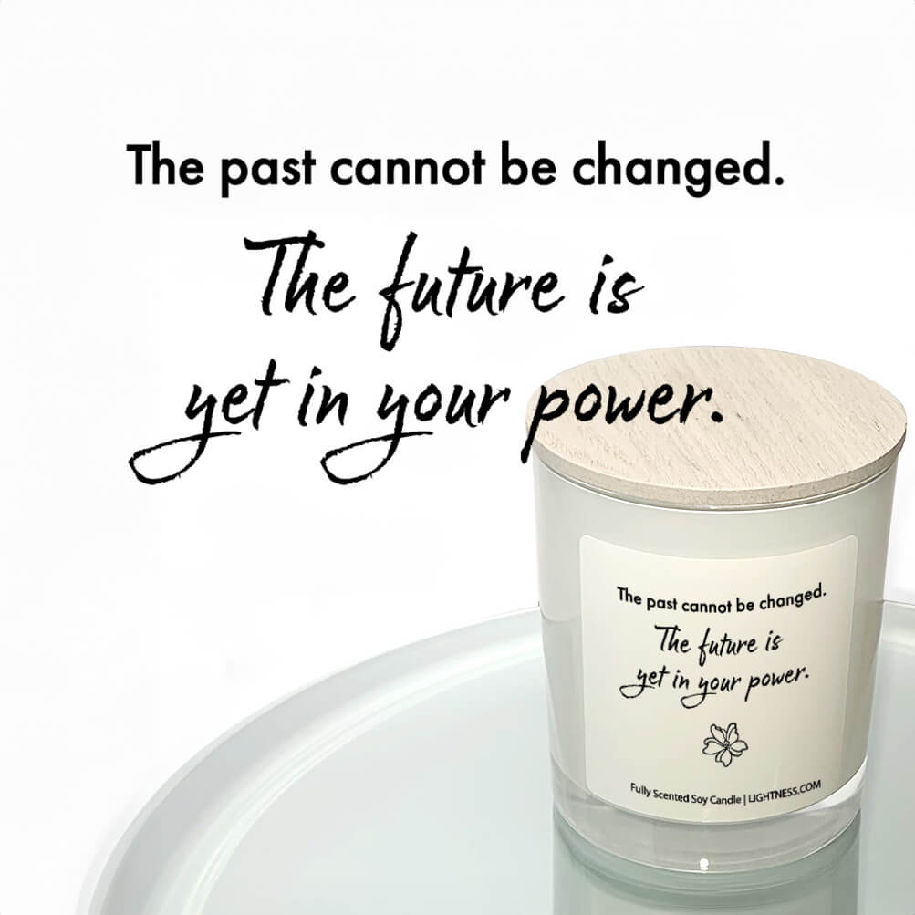 Candle in white glass jar reflected in mirror with motivational quote - The past cannot be changed. The future is yet in your power.