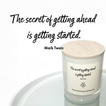 Candle in white glass jar reflected in mirror with motivational quote - The secret of getting ahead is getting started.