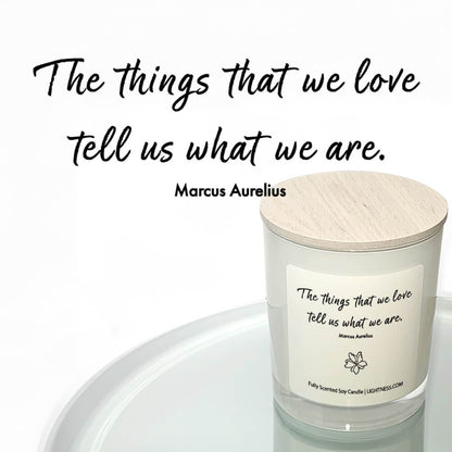 Candle in white glass jar reflected in mirror with motivational quote - The things that we love tell us what we are.